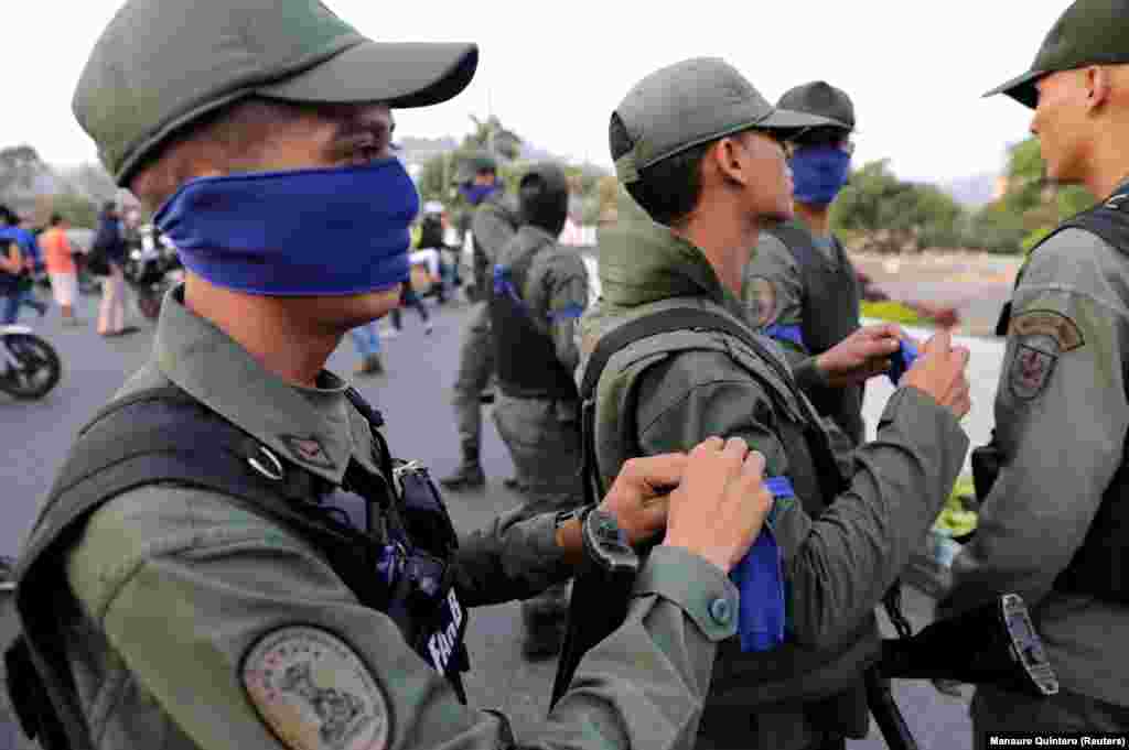 Armed men apparently aligned with Guaido don blue armbands. 