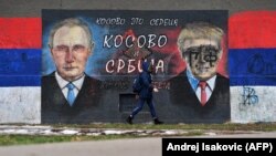 A woman walks past a mural depicting Russian President Vladimir Putin and U.S. President Donald Trump in Belgrade.