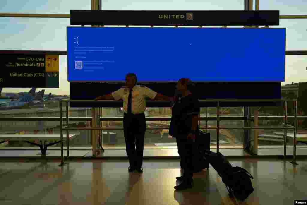 Aeroportul Internațional Newark, New Jersey, SUA – angajați al United Airlines așeaptă lângă un monitor din Terminalul C, care arată „blue error”, defecțiune cunoscută sub numele „Blue Screen of Death”. 19 iulie 2024.