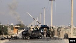 Members of the Afghan security forces walk past the wreck of a burnt-out vehicle en route to the center of Kunduz on October 1.