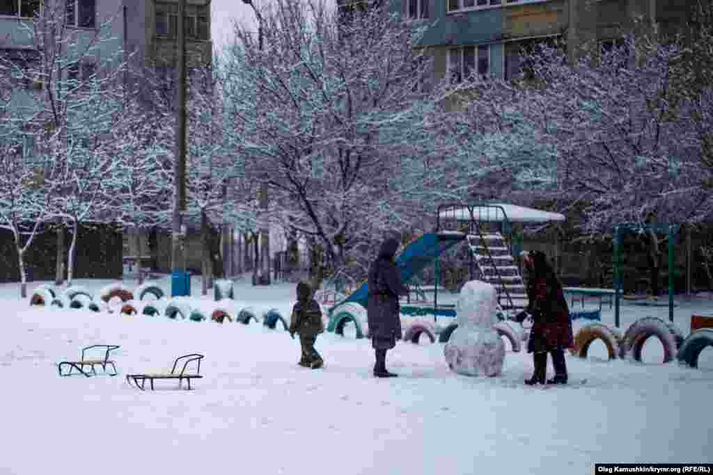 Пока дети играют, взрослые лепят снеговика. 