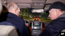 На цьому фото, взятому з відео, опублікованому російським ТБ у неділю, 19 березня 2023 року, президент Росії Володимир Путін (за кермом) і віце-прем’єр-міністр Росії Марат Хуснуллін їдуть на автомобілі окупованим Маріуполем. Перед цим Путін прибув до окупованого Криму, щоб « відзначити дев'яту річницю анексії» українського півострова.