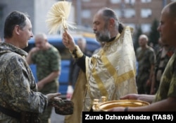 Священик благословляє російського полковника Ігоря Гіркіна (Стрєлкова), який на той час був одним із ватажків угруповання «ДНР», що визнане в Україні терористичним. Окупований Донецьк, 10 липня 2014 року