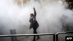 An Iranian woman raises her fist amid the smoke of tear gas at the University of Tehran during a protest driven by anger over economic problems in December 2017.