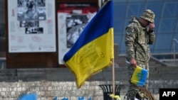Un militar ucrainean plânge lângă un steag ucrainean la un memorial improvizat pentru soldații căzuți în Piața Independenței din Kiev. 10 noiembrie 2023. 