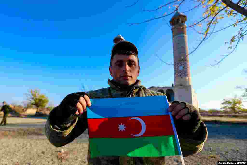 An Azerbaijani poses with his country's flag in front of Agdam mosque on November 24.