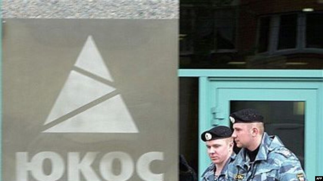 Russian antiriot policemen pass by the Yukos logo during the auction for the sale of the company's key assets at Yukos's Moscow headquarters in May 2007.
