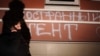 A woman walks past graffiti saying "Foreign agents [love the] USA" on the building used by the Memorial Human Rights Center in Moscow in November 2012. 