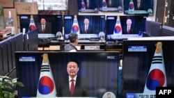  Televizijski ekrani prikazuju obraćanje predsjednika Južne Koreje Yoon Suk Yeola u Seulu 7. decembra 2024. 
