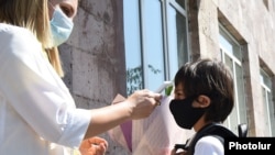 Armenia -- A teacher measures a first grader's temperature at the entrance to a school in Yerevan, September 14, 2020.