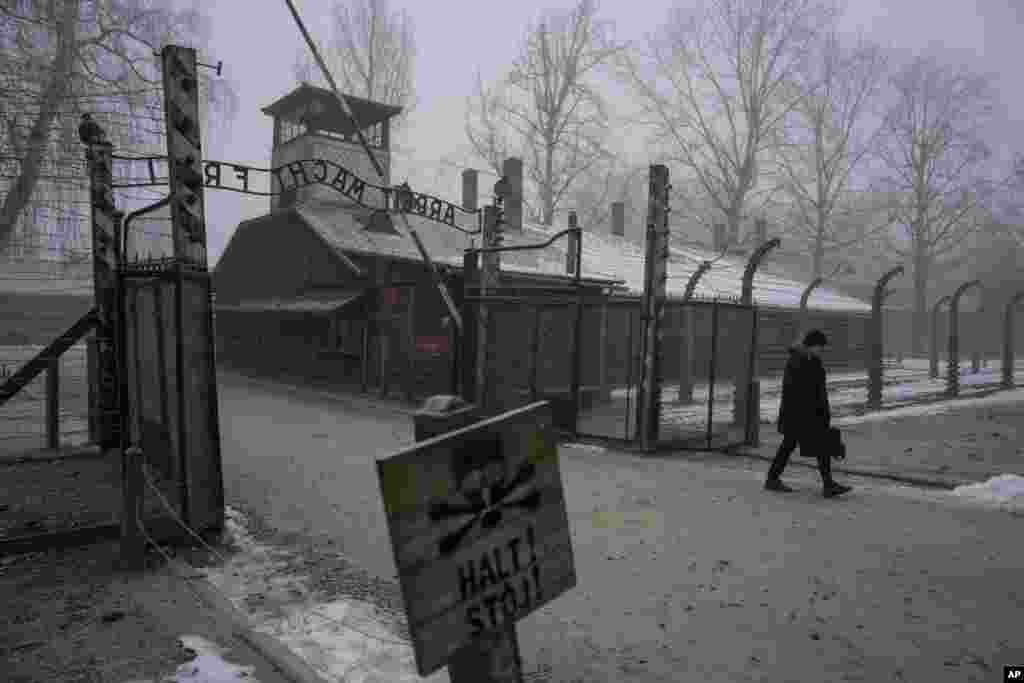 Un bărbat trece pe sub inscripția „Arbeit Macht Frei” (Munca te eliberează) de la poarta Memorialului și Muzeului Auschwitz-Birkenau, un fost lagăr de concentrare și de exterminare german nazist, din Oswiecim, Polonia, joi, 23 ianuarie 2025. 