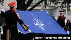 Members of an honor guard raise the NATO flag in front of North Macedonia's parliament to mark the ratification of accession to the alliance in Skopje on February 11.