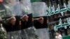 Мальчик-уйгур сидит возле магазина, наблюдая, как китайские солдаты идут по улице Урумчи, 12 июля 2009 года. 