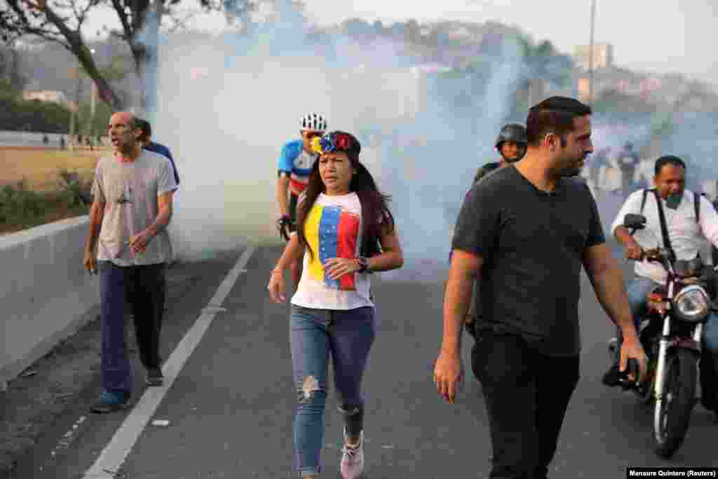 People run away from tear gas near the Generalisimo Francisco de Miranda Air Base. 