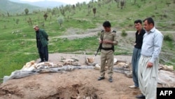 Kurdish security officers look at the damage to a roof following suspected Iranian shelling on Narmalas, close to the Iran-Iraq border.