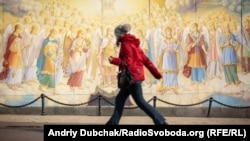 Жінка в масці проходить біля Михайлівського Золотоверхого собору в Києві, який належить Православній церкві України
(фото минулорічне)