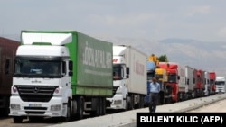 A man walks beside trucks waiting to cross into Iran from the Turkish side of the border near the Gurbulak border crossing between Turkey and Iran on June 27, 2012, at Dogubeyazit.