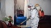 A municipal worker wearing protective gear sprays disinfectant as a preventive measure against the spread of the COVID-19 coronavirus at a local radio station in the northeastern Kunduz Province on June 3.