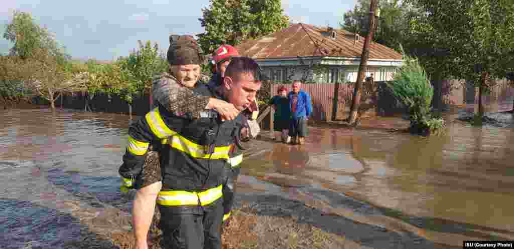 Пожарникар носи постара жена на грб во градот Кудалби, област Галати, 14 септември 2024 година. 